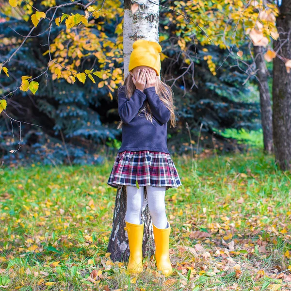 Malá holka hraje na schovávanou v podzimním lese — Stock fotografie