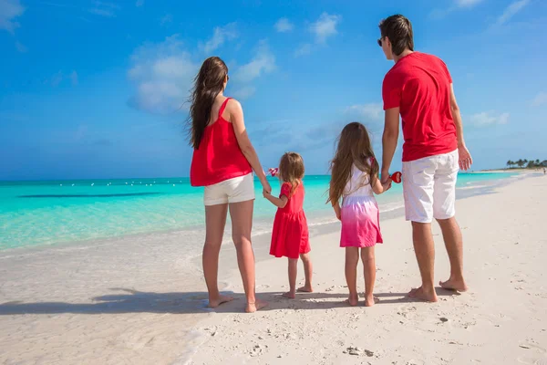 Lycklig familj av fyra på stranden i röda santa hattar — Stockfoto