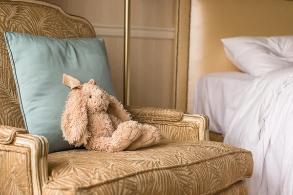 Soft plush toy bunny on a chair in a hotel room — Stock Photo, Image