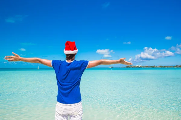 Jonge man in Kerstman hoed op tropisch strand — Stockfoto