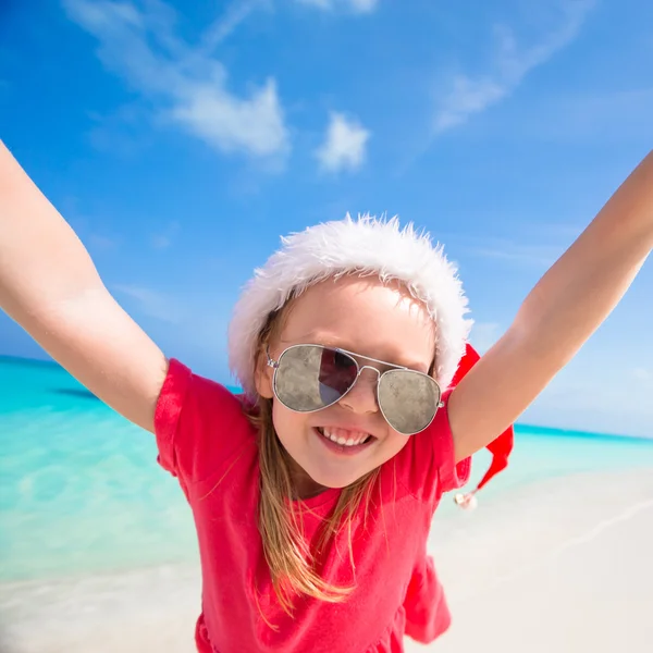 Kırmızı Noel Baba şapkası, küçük sevimli kız plajda eğlence var — Stok fotoğraf