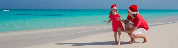 Liten flicka och glad pappa i santa hatt på exotiska beach — Stockfoto