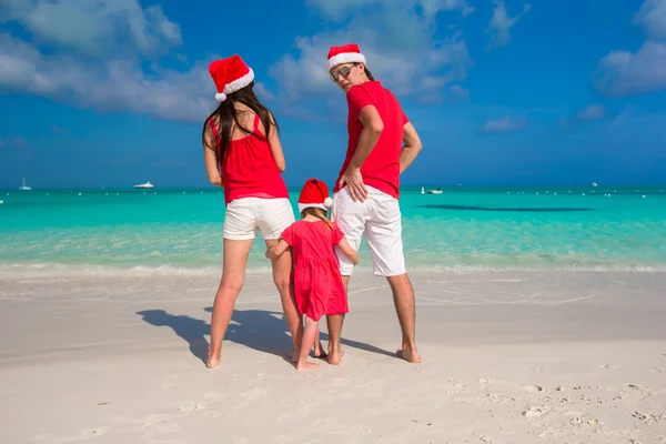 Dreiköpfige glückliche Familie mit Weihnachtsmützen im Tropenurlaub — Stockfoto