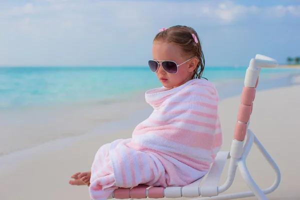 Entzückendes kleines Mädchen mit Handtuch bedeckt sitzt auf Strandkorb — Stockfoto