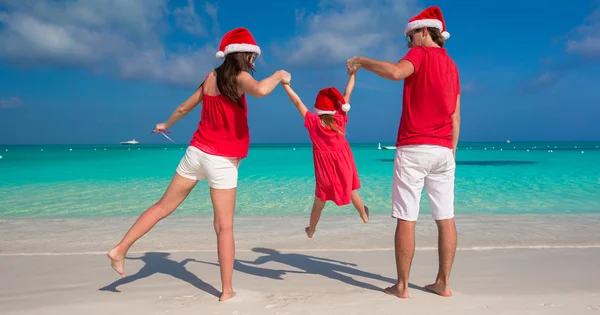 Dreiköpfige glückliche Familie mit Weihnachtsmützen im Tropenurlaub — Stockfoto