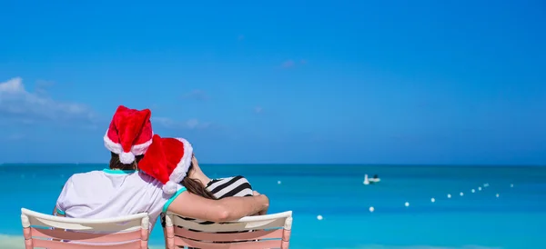 Widok z tyłu para w santa kapelusze cieszyć się wakacje na plaży — Zdjęcie stockowe