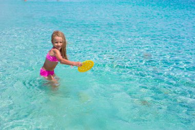 Küçük kız denizde sırasında tatil tropikal frizbi oynamaya