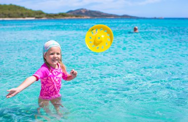 Küçük kız denizde sırasında tatil tropikal frizbi oynamaya
