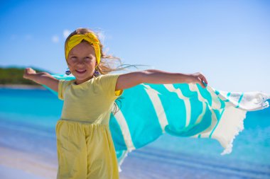 Küçük kız tropikal tatilde plaj havlusuyla eğleniyor.