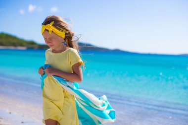 Küçük kız tropikal tatilde plaj havlusuyla eğleniyor.