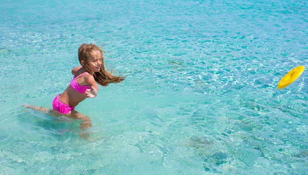 Küçük kız frizbi tropikal beyaz kumsalda tatil sırasında oynamaya. — Stok fotoğraf