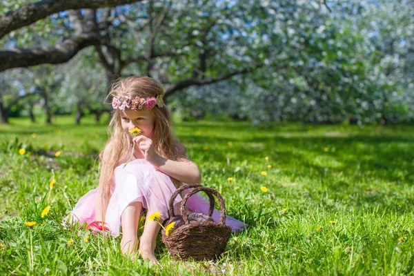 Nettes kleines Mädchen im blühenden Apfelgarten an einem sonnigen Frühlingstag — Stockfoto