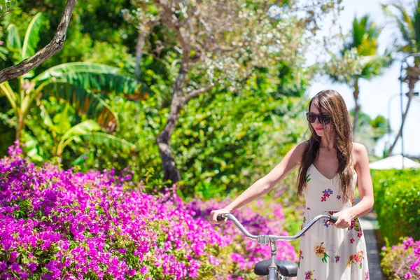 Junge Frau radelt im Urlaub durch blühenden Garten — Stockfoto