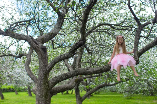 Little adorable girl sitting on blossoming apple tree — Stock Photo, Image