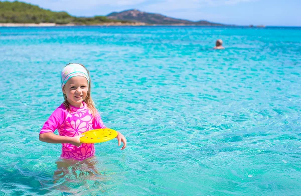 Küçük kız denizde sırasında tatil tropikal frizbi oynamaya — Stok fotoğraf