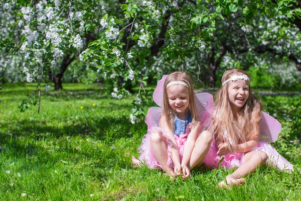 Little girls with butterfly wings in the blossoming apple orchard — Stock Photo, Image