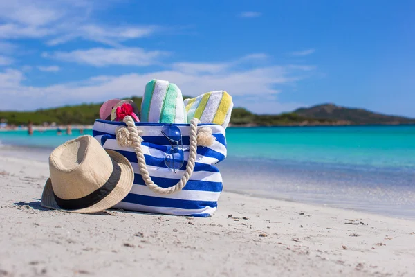 Bolso azul, sombrero de paja, chanclas y toalla en la playa tropical blanca — Foto de Stock