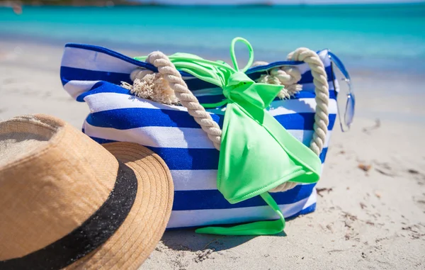 Borsa a righe, cappello di paglia, crema solare e frisbee sulla spiaggia tropicale di sabbia bianca — Foto Stock