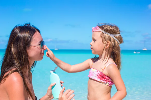 Niña aplicando crema protector solar en la nariz de su madre — Foto de Stock