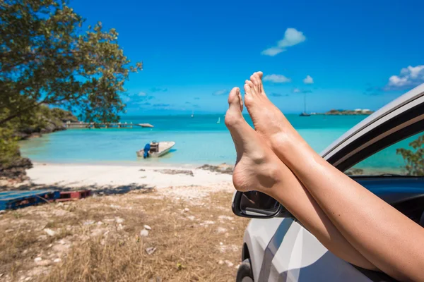 Feminino descalço a partir da janela de um carro no fundo praia tropical — Fotografia de Stock