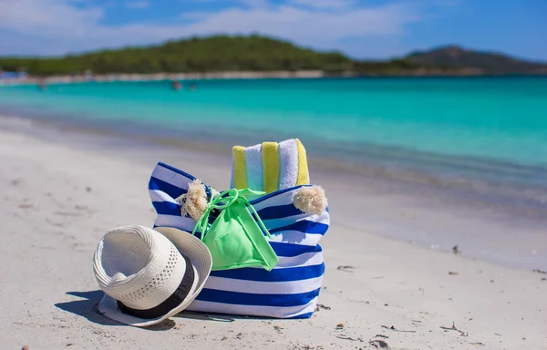 Borsa a righe, cappello di paglia, crema solare e frisbee sulla spiaggia tropicale di sabbia bianca — Foto Stock