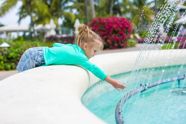 Pequena menina adorável em um belo hotel exótico perto da fonte — Fotografia de Stock