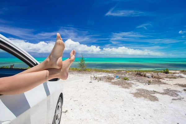 Mujer descalza desde la ventana de un coche en la playa tropical de fondo —  Fotos de Stock