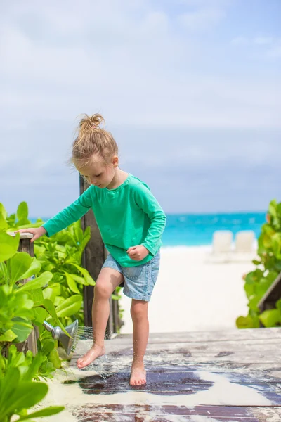 Schattig meisje wast uit het zand van haar voeten op tropisch strand — Stockfoto