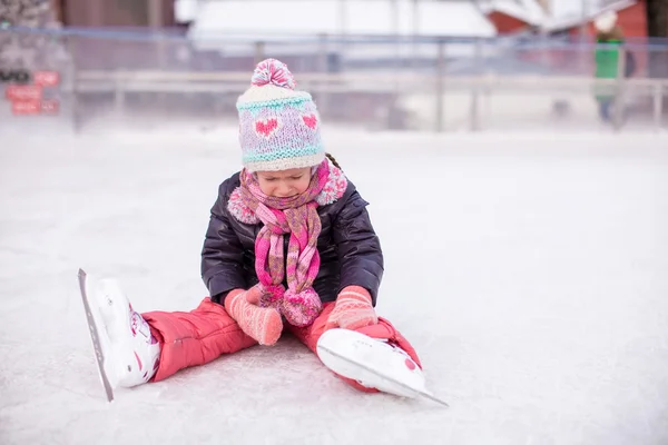 Little sad girl sitting on skating rink after the fall — Stock Photo, Image