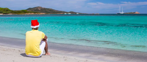 Молодой человек в шляпе Санты во время пляжного отдыха — стоковое фото