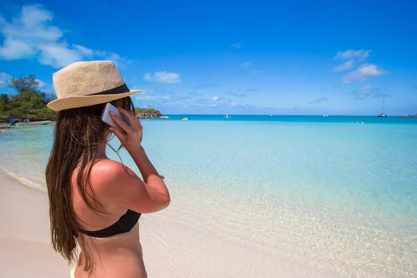 Молодая женщина разговаривает по телефону на тропическом пляже — стоковое фото