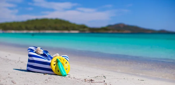 Полосатый мешок, соломенная шляпа, солнцезащитный крем и фрисби на белом песчаном тропическом пляже — стоковое фото