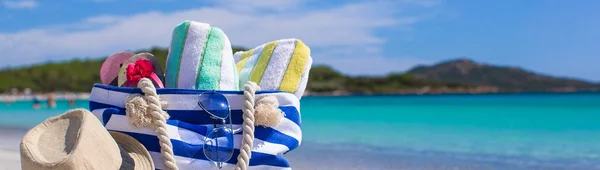 Saco azul, chapéu de palha, chinelos e toalha na praia tropical branca — Fotografia de Stock
