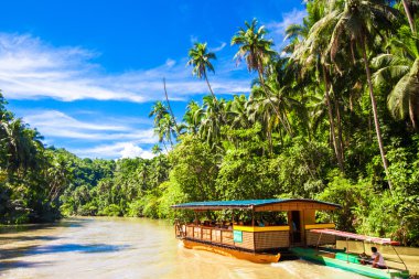 Exotic cruise boat with tourists on jungle river Loboc, Bohol clipart