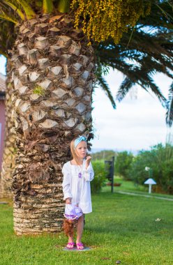 Gün batımında egzotik bir tatil köyünde sevimli küçük bir kız.