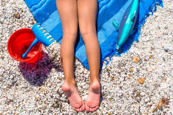 Close-up van kleine meisje benen op tropisch strand met steentjes — Stockfoto
