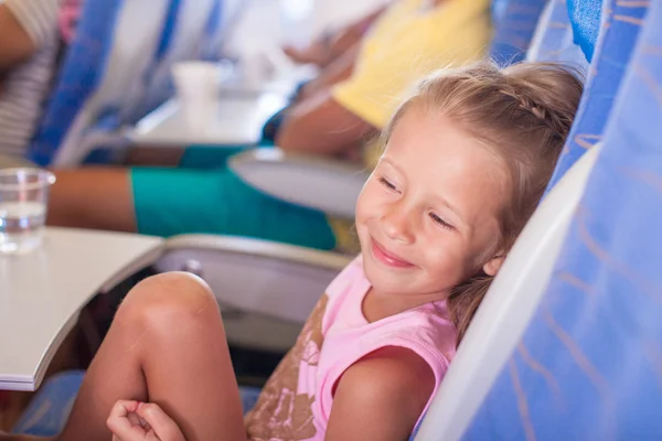 Kleines lächelndes glückliches Mädchen im Flugzeug — Stockfoto