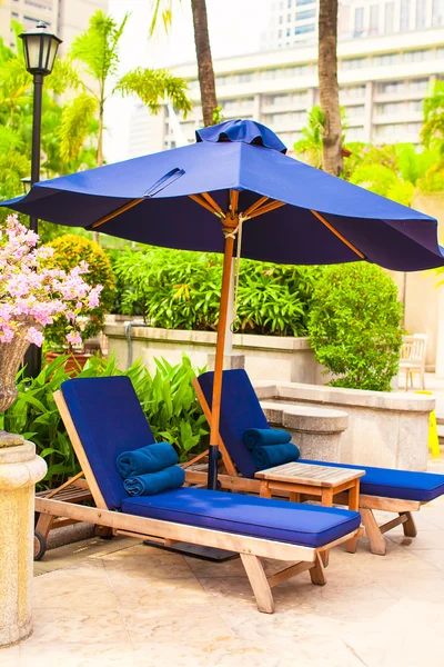 Solstolar med parasoller i exotiska resort nära pool — Stockfoto