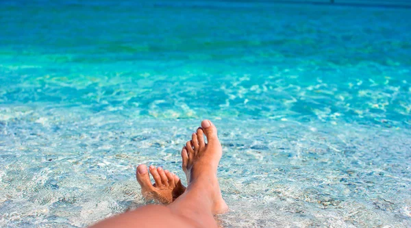 Closeup of female legs background of the turquoise sea — Stock Photo, Image