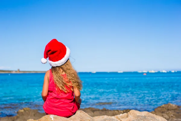 Menina adorável em chapéu de Natal durante as férias na praia — Fotografia de Stock