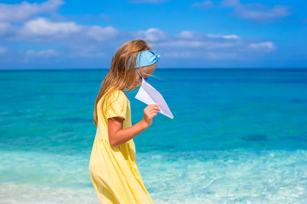 Bonne petite fille jouer avec avion en papier sur la plage de sable blanc — Photo