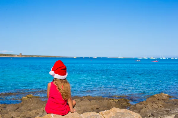 Carina bambina a Babbo Natale cappello sulla spiaggia durante le vacanze — Foto Stock