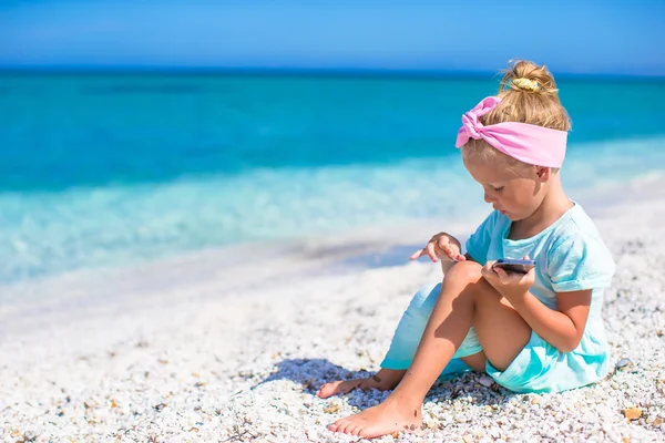 Little adorable girl playing in phone during beach vacation — Stock Photo, Image