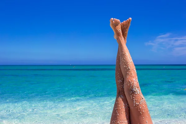 Närbild på kvinnliga ben bakgrunden av det turkosa havet — Stockfoto