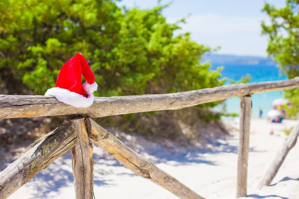 Red christmas hat on on fence background turquoise sea — Stock Photo, Image