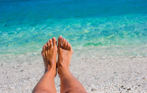 Närbild av kvinnliga ben bakgrunden av det turkosa havet — Stockfoto
