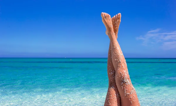 Fechar o fundo das pernas femininas do mar azul-turquesa — Fotografia de Stock