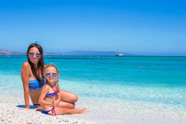Gelukkig moeder en haar schattige kleine dochter tijdens de zomervakantie op het strand — Stockfoto