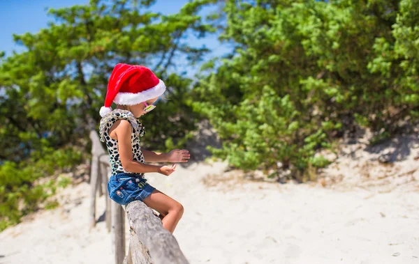 Menina bonito em chapéu de Natal durante as férias na praia — Fotografia de Stock