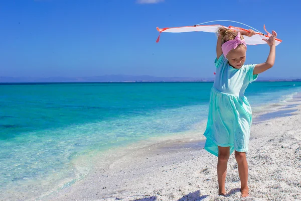 Little happy girl playing with flying kite on tropical beach — Stock Photo, Image
